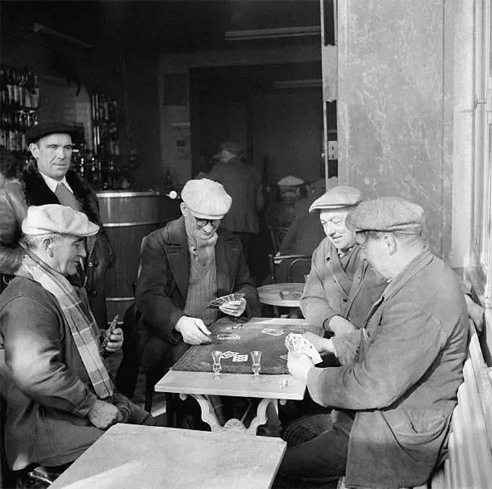 Group of people playing belote around a table in a bar