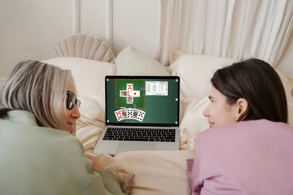 Two people in front of a screen, discovering the game of belote together